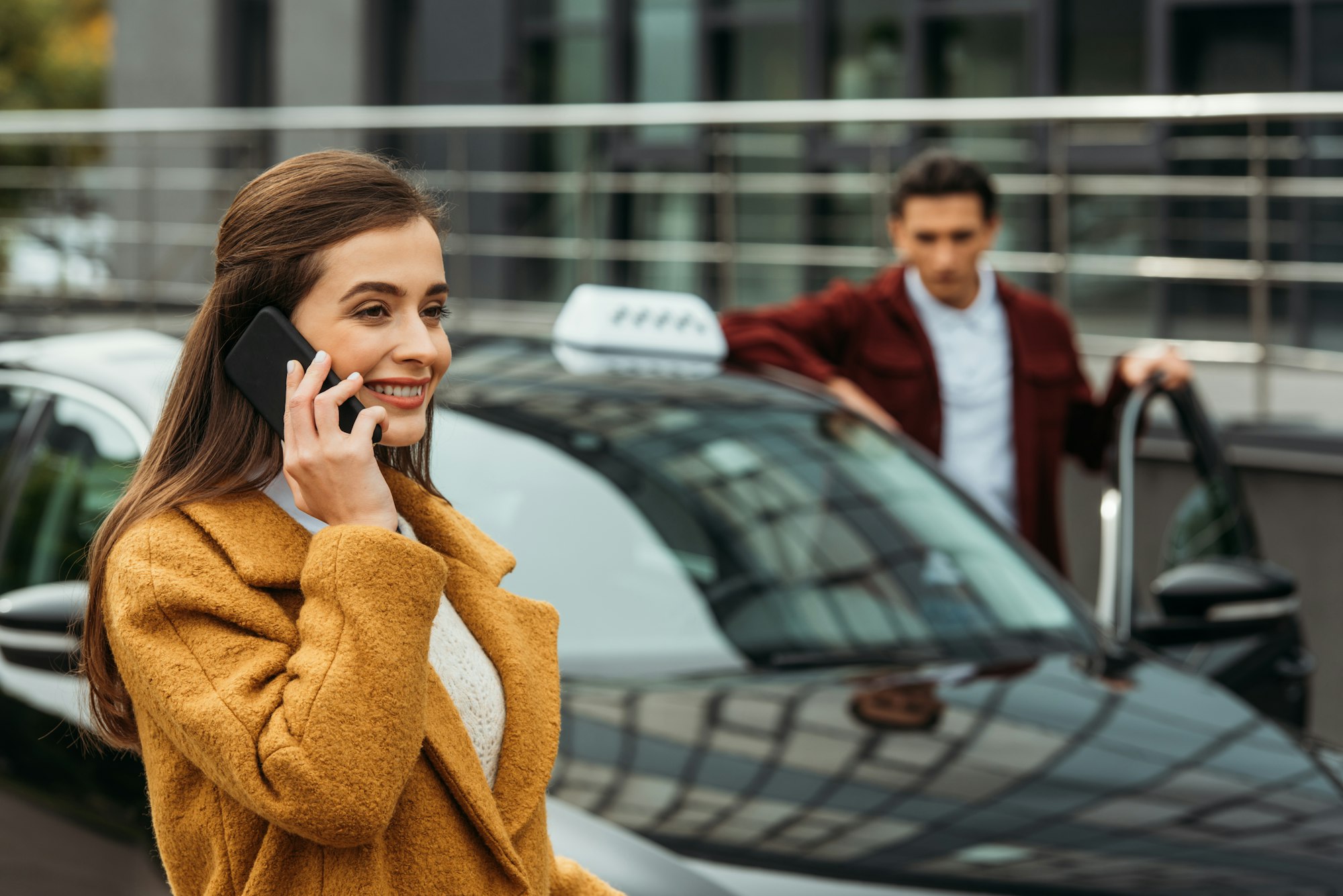 Selective focus of woman talking on smartphone and taxi driver at background